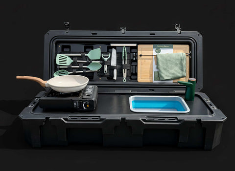 Portable outdoor kitchen set with cookware and utensils in a black case on a dark background
