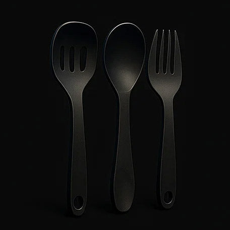 Black kitchen utensils including a spoon, fork, and spatula on a black background