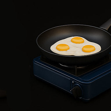 Frying pan with three eggs on a portable stove against a black background